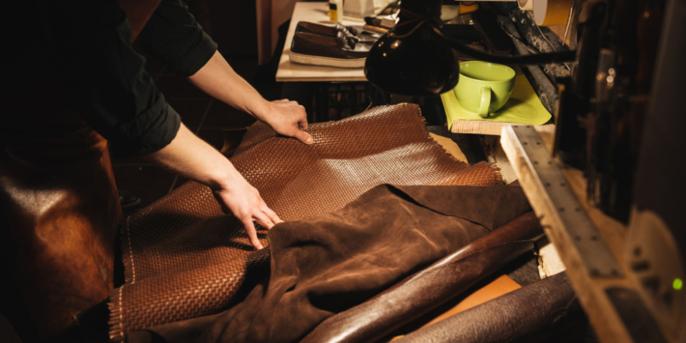 Cropped image of young man shoemaker at footwear workshop.